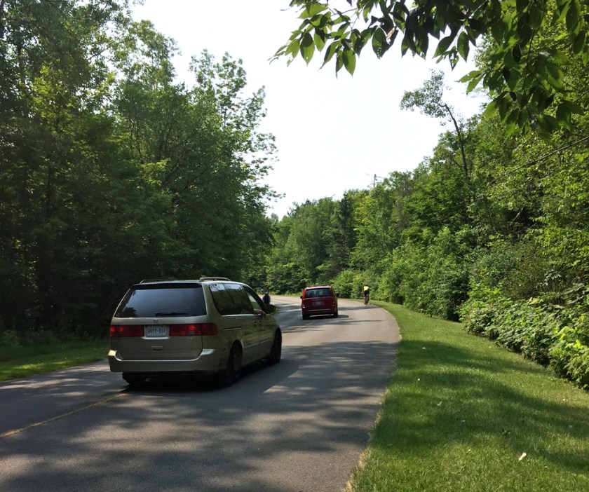 Cars passing cyclists along Gatineau Parkway